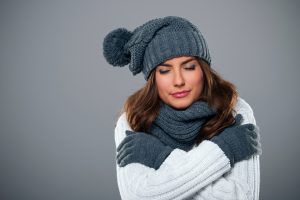 cold-woman-wearing-scarf-hat-gloves-inside-house
